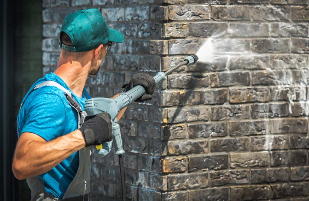 House Brick Wall Washing Using Pressure Washer. Caucasian Worker in His 30s. 
Pressure Washing Pollen