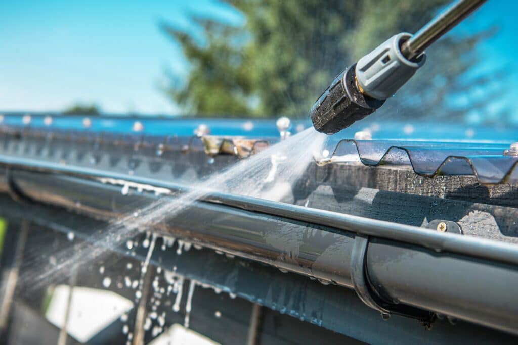 Spring Rain Gutters Cleaning Using Pressure Washer. Closeup Photo. Removing Tiger Stripes
