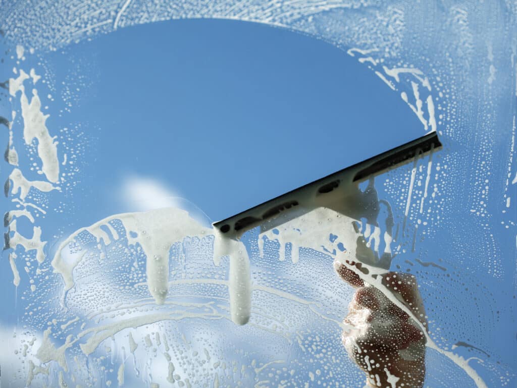 Window cleaner using a squeegee to wash a window. right professional window cleaner