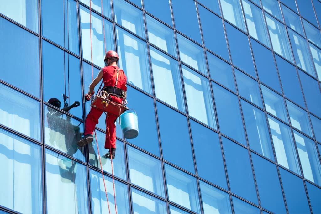 window cleaner working on a glass facade modern skyscraper. Professional Residential Window Washing
